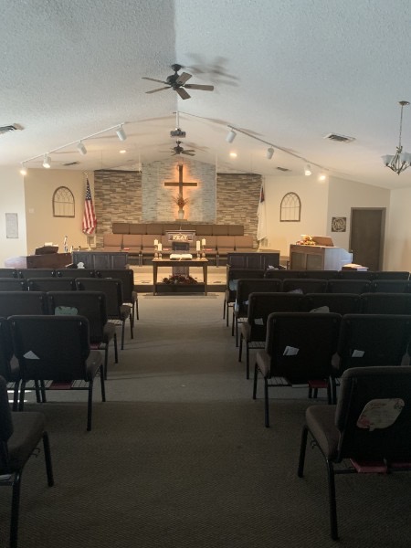 Faith Baptist Church sanctuary viewed from the center aisle toward the pulpit and cross.